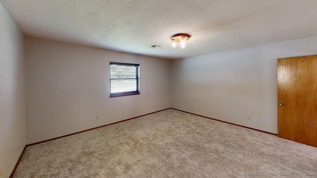 carpeted empty room with visible vents, a textured ceiling, and baseboards