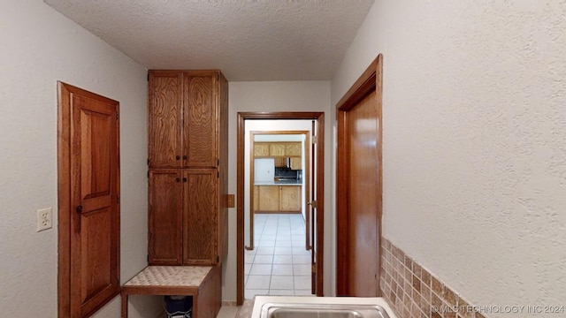 hall featuring a textured ceiling and light tile patterned flooring