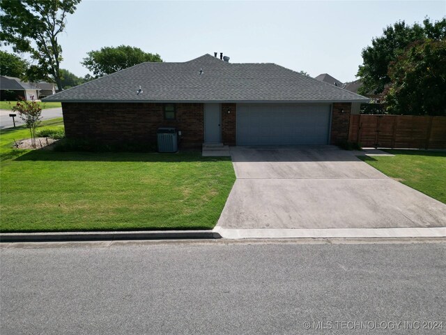 ranch-style house with central AC unit, concrete driveway, fence, a front yard, and brick siding