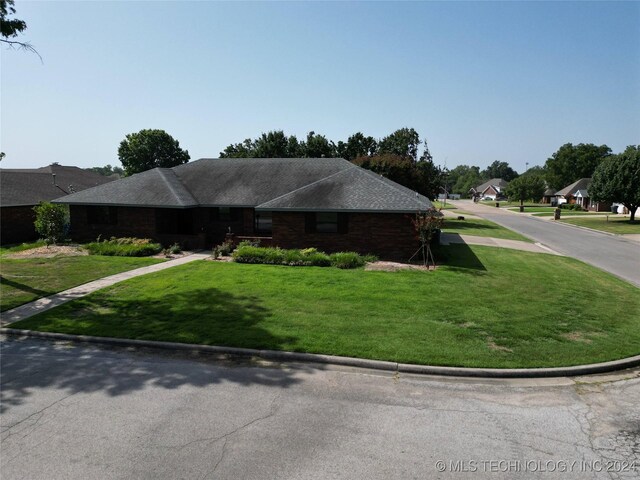 single story home with roof with shingles and a front yard