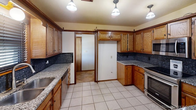 kitchen featuring appliances with stainless steel finishes, decorative backsplash, light stone counters, pendant lighting, and sink