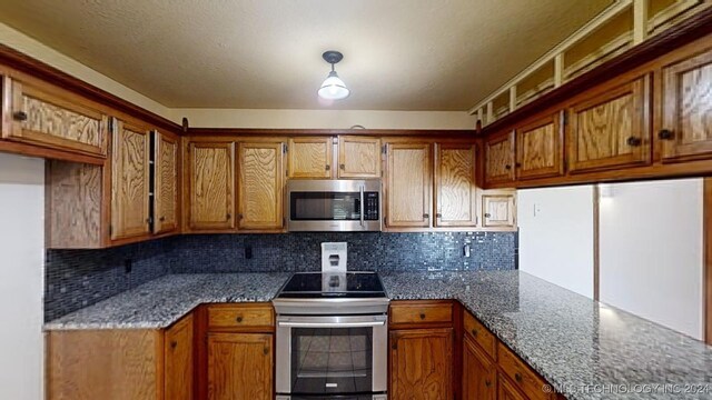 kitchen featuring decorative backsplash, dark stone countertops, and appliances with stainless steel finishes