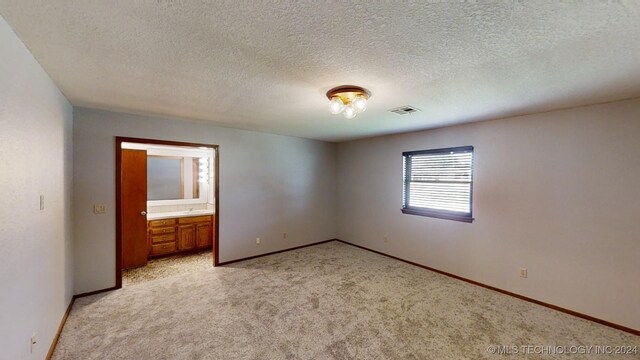 unfurnished bedroom with light carpet, a textured ceiling, visible vents, and baseboards