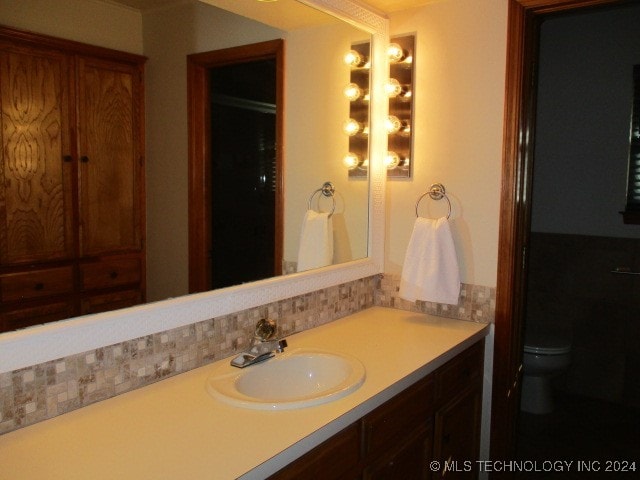 bathroom featuring toilet, backsplash, and vanity