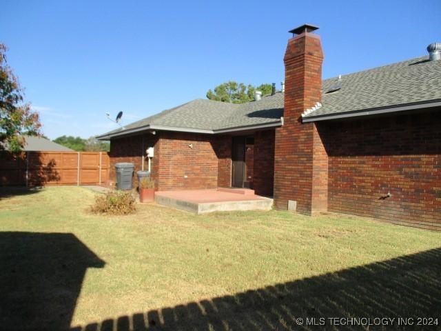 back of house with a patio area, a yard, fence, and brick siding