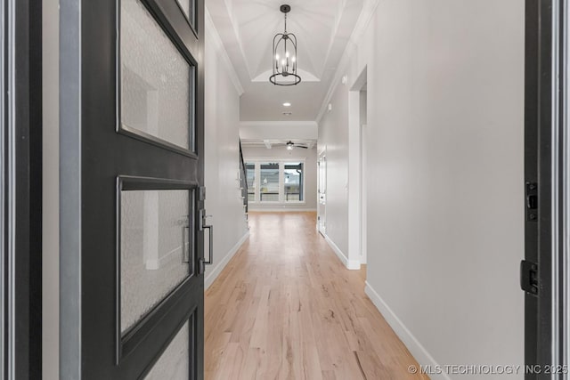 hall featuring an inviting chandelier, light wood-style flooring, ornamental molding, and baseboards