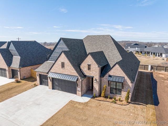 french country style house featuring brick siding, a shingled roof, concrete driveway, fence, and a residential view