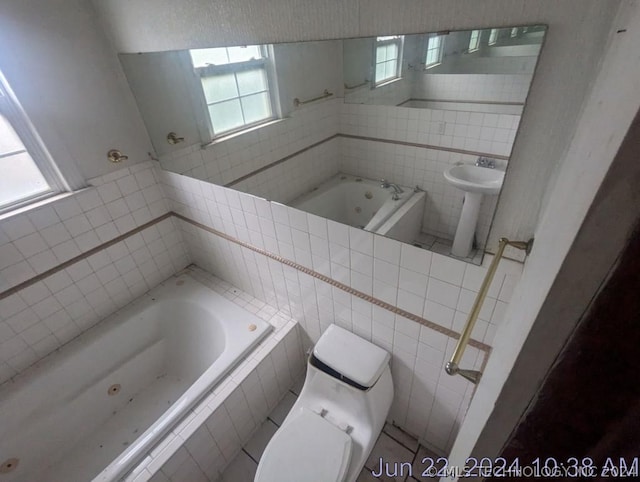 bathroom featuring sink, tile walls, tiled bath, and toilet