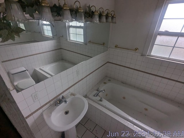 bathroom with tiled bath, tile patterned floors, sink, and tile walls