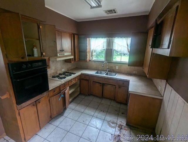 kitchen featuring light tile patterned flooring, white gas stovetop, decorative backsplash, oven, and sink