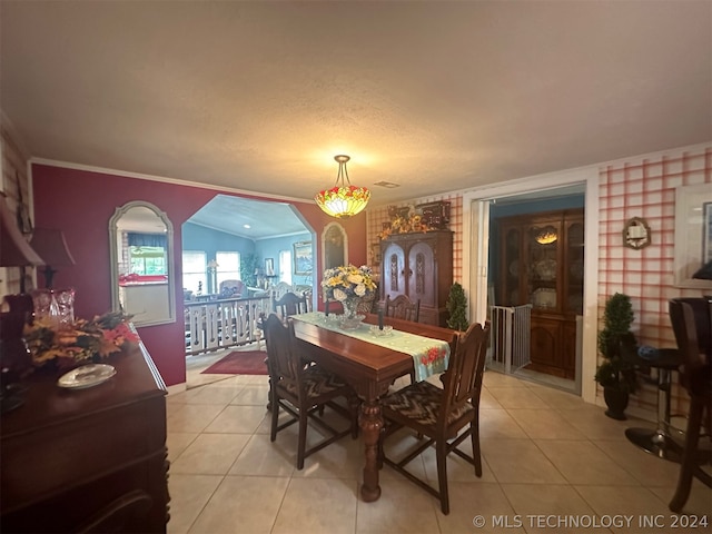 dining room featuring light tile patterned flooring, lofted ceiling, crown molding, a textured ceiling, and brick wall