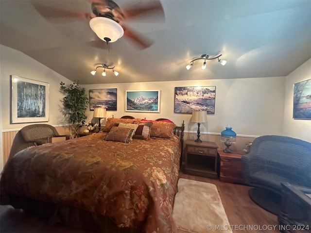 bedroom with ceiling fan, rail lighting, hardwood / wood-style flooring, and vaulted ceiling