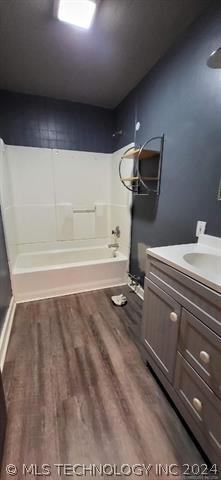 bathroom with wood-type flooring, vanity, and  shower combination