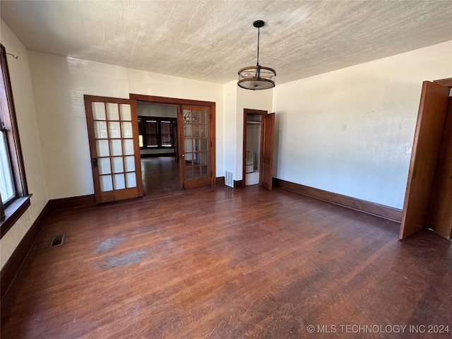 unfurnished dining area with french doors, dark hardwood / wood-style floors, and a textured ceiling