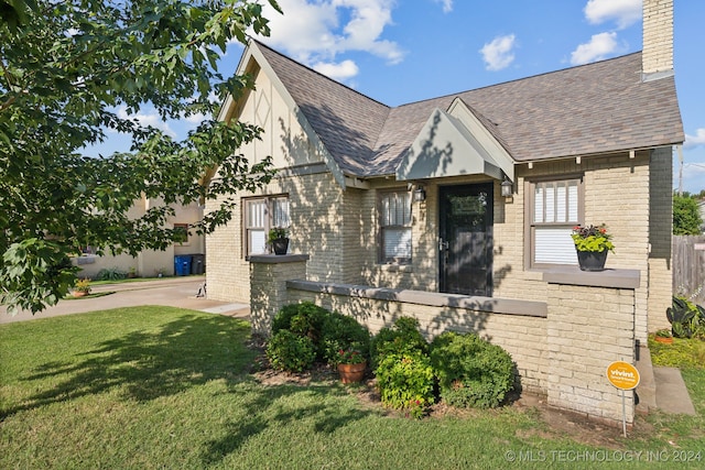 tudor-style house featuring a front lawn