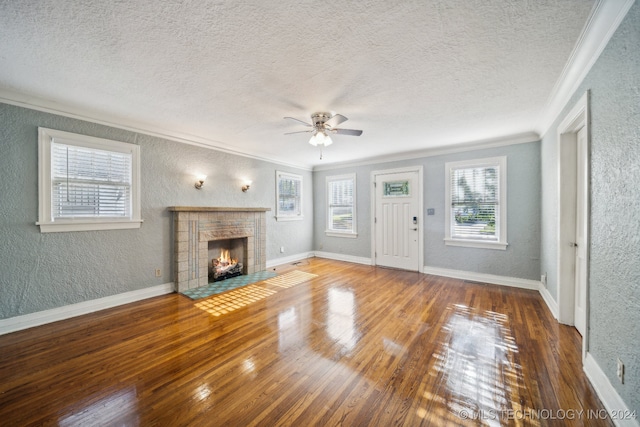 unfurnished living room with a brick fireplace, ceiling fan, hardwood / wood-style floors, crown molding, and a textured ceiling