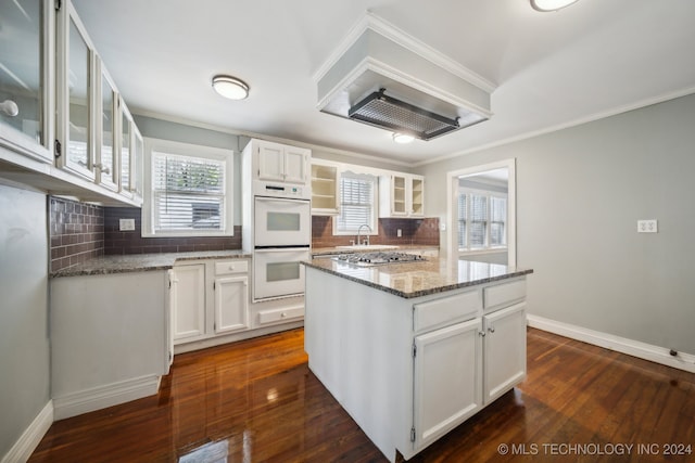 kitchen with dark stone counters, white cabinetry, a center island, and backsplash