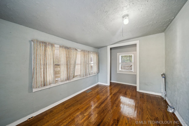 unfurnished room with a textured ceiling and dark hardwood / wood-style flooring