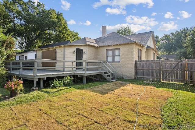 rear view of property with a wooden deck and a lawn