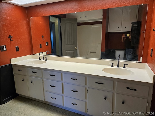 bathroom with dual vanity, toilet, and tile patterned flooring