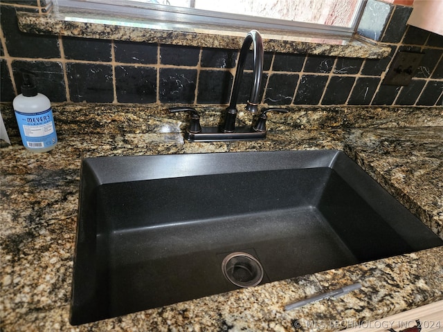 exterior details featuring sink and tasteful backsplash