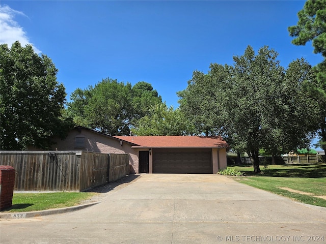 view of front of property with a garage, driveway, fence, and a front lawn