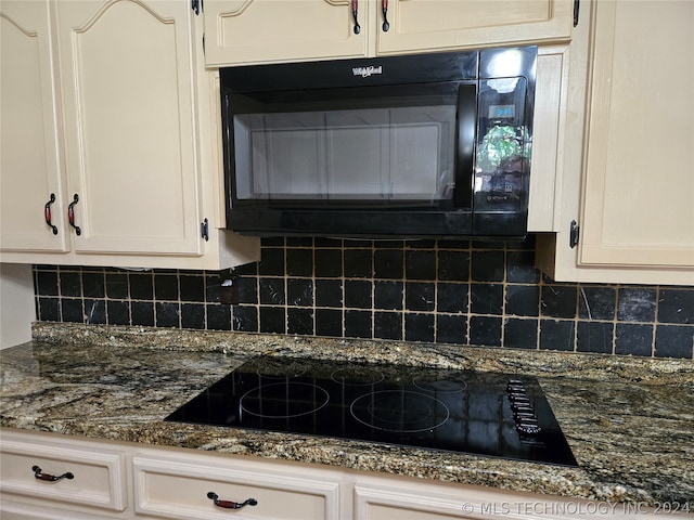 kitchen featuring white cabinets, backsplash, black appliances, and dark stone counters