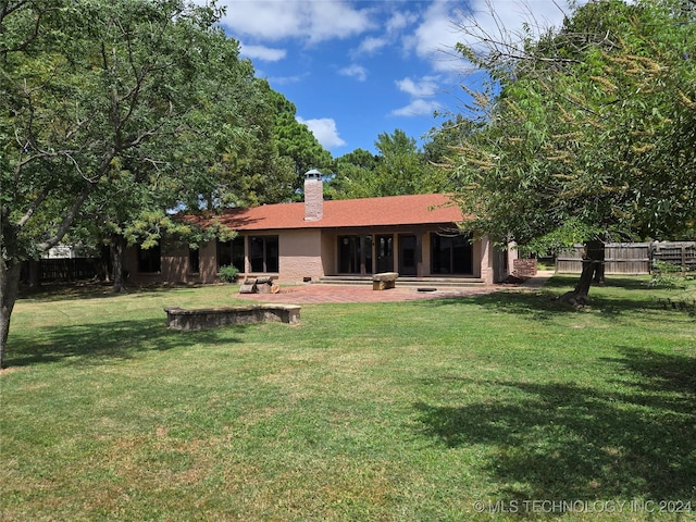 rear view of house with a lawn, a chimney, and fence