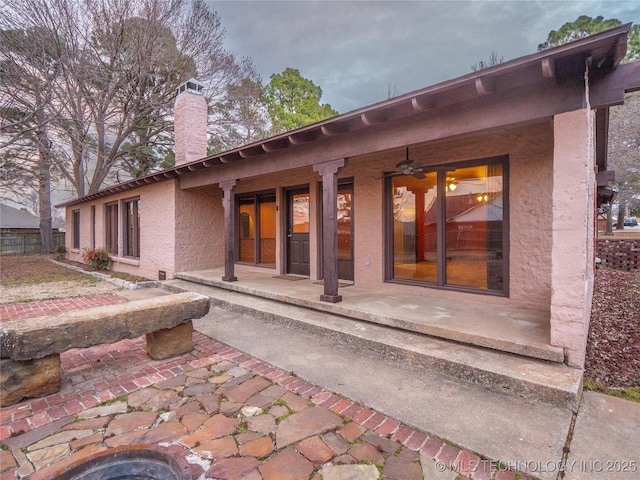 back of house featuring ceiling fan and a chimney