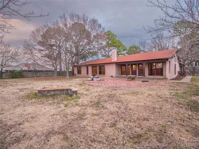 rear view of house with brick siding, fence, and a chimney