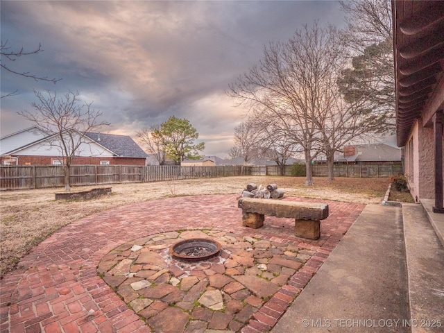 patio terrace at dusk featuring an outdoor fire pit and a fenced backyard