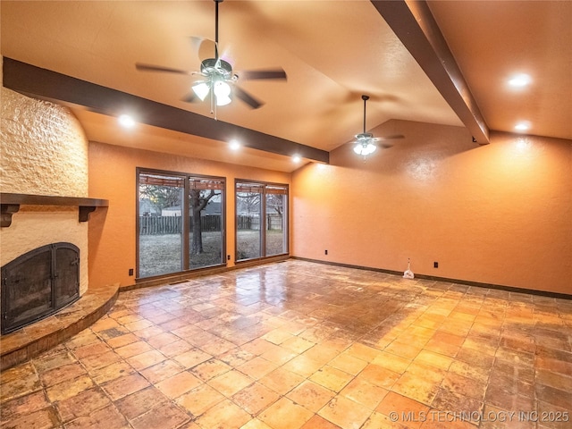 unfurnished living room with stone tile flooring, lofted ceiling with beams, a ceiling fan, a large fireplace, and baseboards