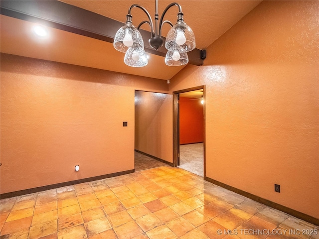 spare room with lofted ceiling, a textured wall, and baseboards