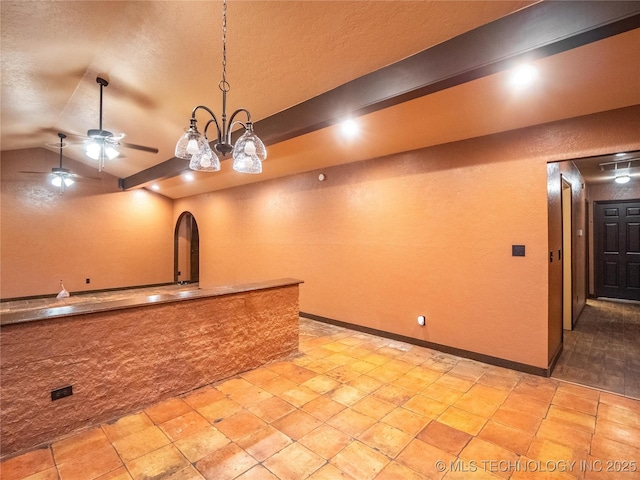 kitchen with baseboards, a ceiling fan, a textured wall, lofted ceiling, and a textured ceiling