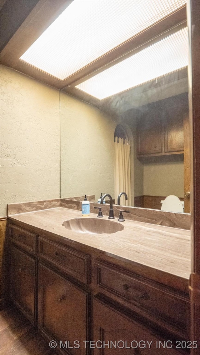 bathroom featuring a textured wall and vanity