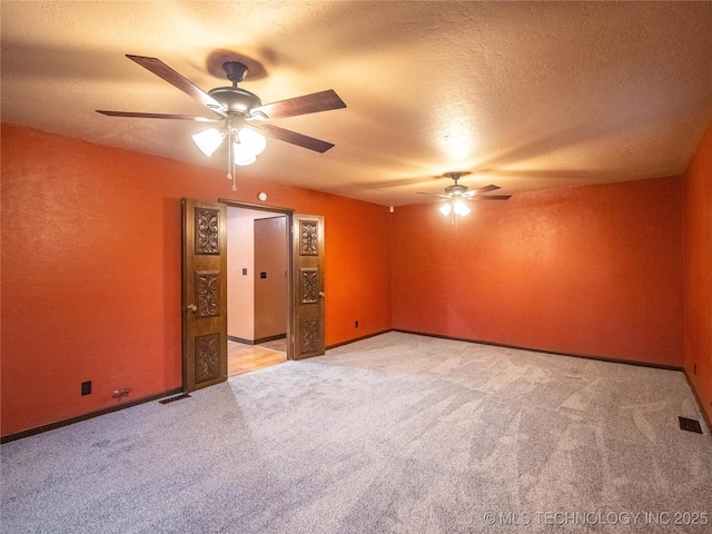 spare room featuring a ceiling fan, visible vents, light colored carpet, and a textured ceiling