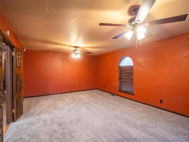 empty room with a textured ceiling, visible vents, a ceiling fan, baseboards, and carpet