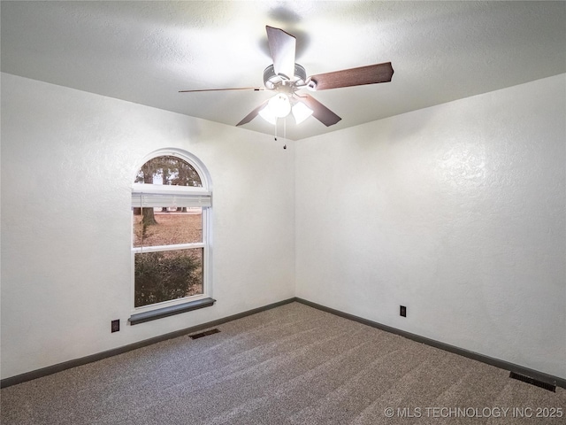 empty room featuring carpet, a textured ceiling, visible vents, and baseboards