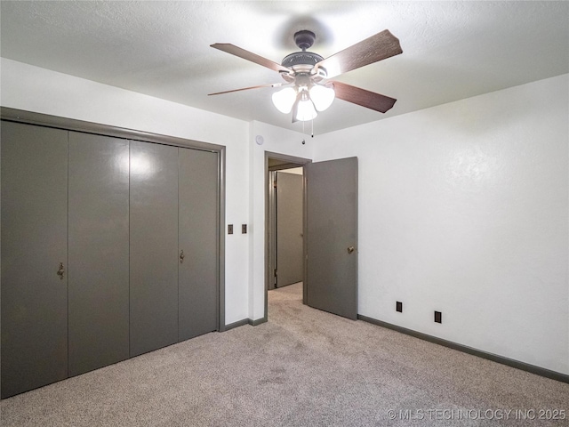 unfurnished bedroom with light carpet, a closet, a textured ceiling, and baseboards