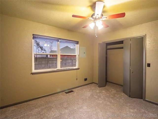 unfurnished bedroom with a textured wall, carpet, visible vents, and baseboards