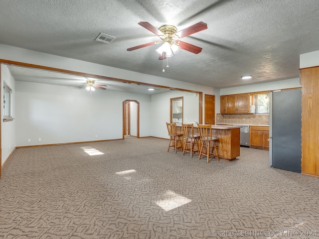 kitchen with tasteful backsplash, appliances with stainless steel finishes, a kitchen breakfast bar, and light carpet