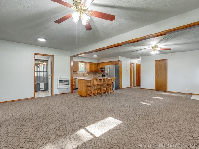 unfurnished living room featuring heating unit, ceiling fan, light carpet, and a textured ceiling