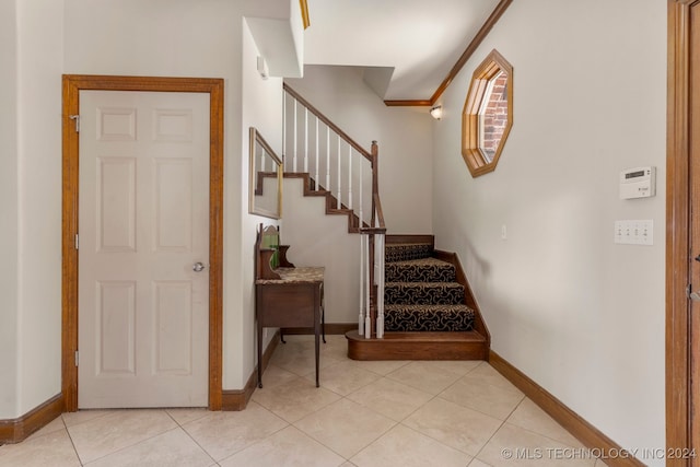 staircase featuring ornamental molding and tile patterned floors