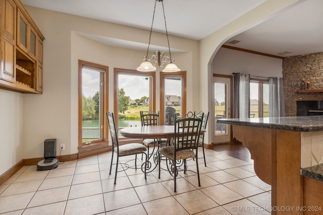 dining area with light tile patterned flooring, a stone fireplace, and an inviting chandelier