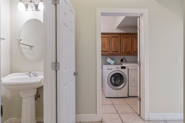 clothes washing area featuring sink, light tile patterned floors, and washer and dryer