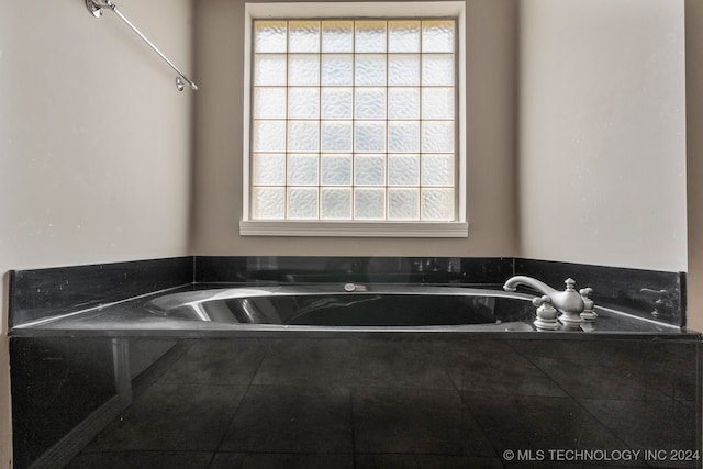 bathroom featuring tiled tub and a wealth of natural light