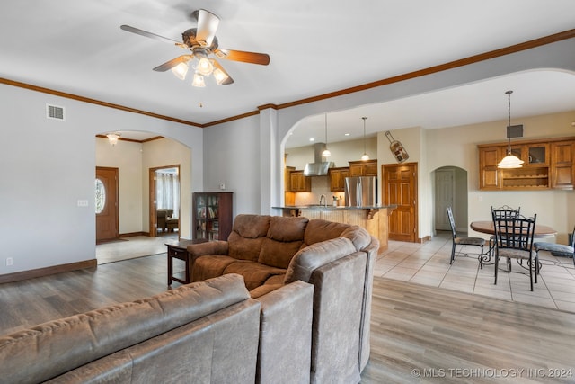 living room featuring ornamental molding, ceiling fan, sink, and light hardwood / wood-style flooring