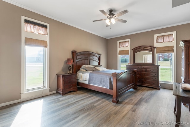 bedroom featuring ceiling fan, hardwood / wood-style flooring, ornamental molding, and multiple windows