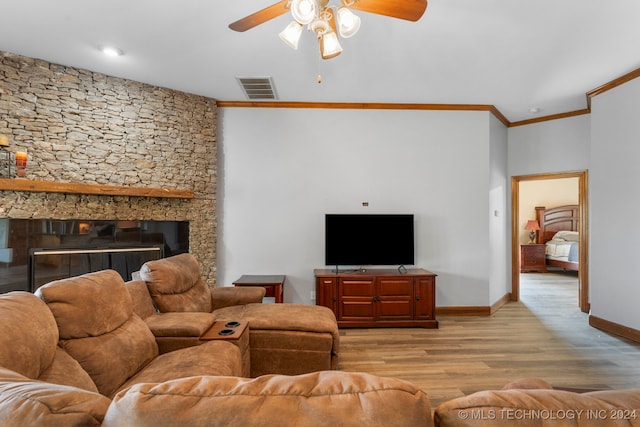 living room featuring ceiling fan, crown molding, light hardwood / wood-style flooring, and a stone fireplace