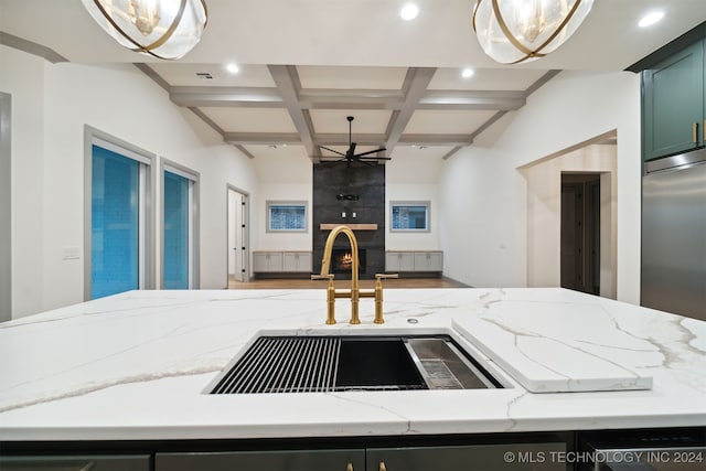 kitchen with sink, decorative light fixtures, a fireplace, and stainless steel built in refrigerator